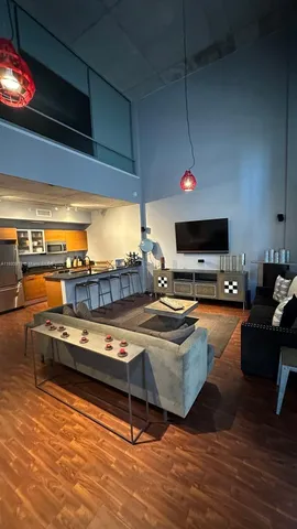 a living room with furniture flat screen tv and kitchen view