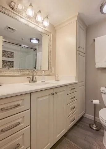 a bathroom with a double vanity sink a mirror and a toilet