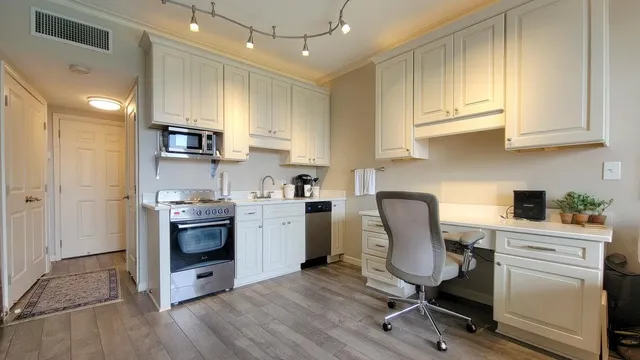 a kitchen with stainless steel appliances kitchen island granite countertop a sink cabinets and wooden floor
