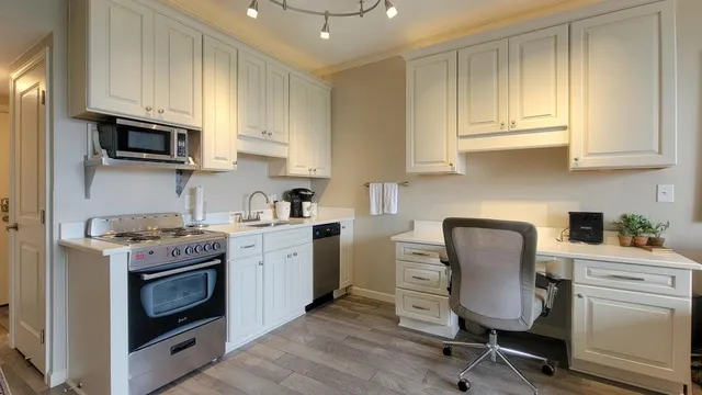 a kitchen with stainless steel appliances granite countertop a stove top oven a sink dishwasher and white cabinets with wooden floor