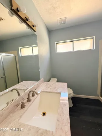 a bathroom with a granite countertop sink a toilet a mirror and vanity