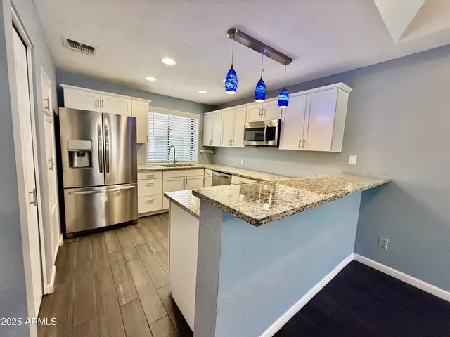 a kitchen with stainless steel appliances granite countertop a refrigerator a stove and a sink