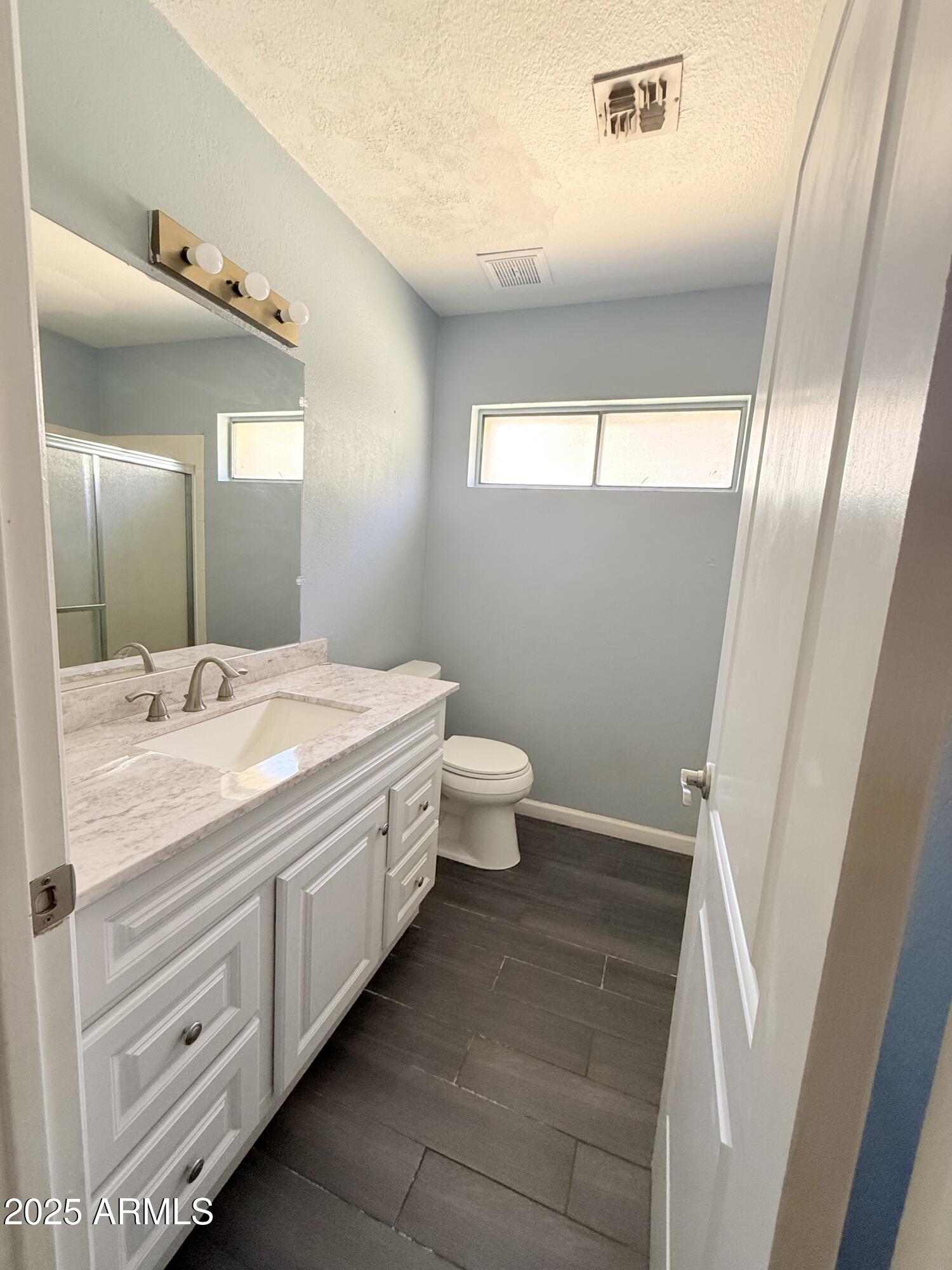 11666 North 28th Drive, Unit 155 Phoenix, AZ 85029 - Photo 21 of 28 a bathroom with a granite countertop sink a toilet a mirror and vanity