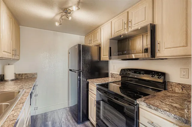 a kitchen with granite countertop a stove sink and refrigerator