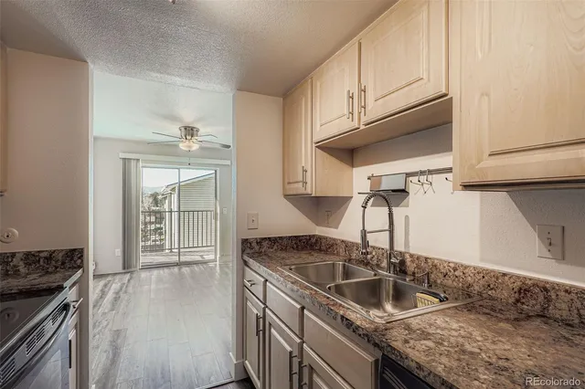 a kitchen with granite countertop a sink dishwasher stove and cabinets