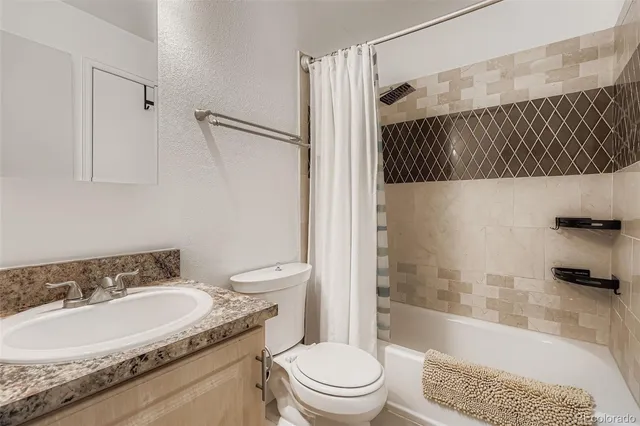a bathroom with a granite countertop sink a toilet and shower
