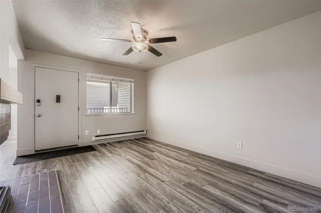 an empty room with wooden floor chandelier fan and windows