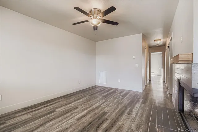 an empty room with wooden floor and a ceiling fan