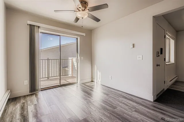 an empty room with wooden floor a ceiling fan and windows