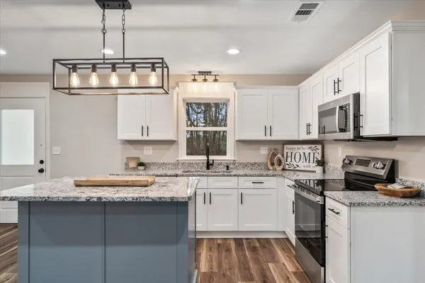 a kitchen with granite countertop a sink a counter space appliances and cabinets