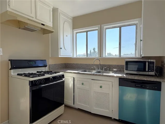 a kitchen with granite countertop stainless steel appliances a sink stove and cabinets