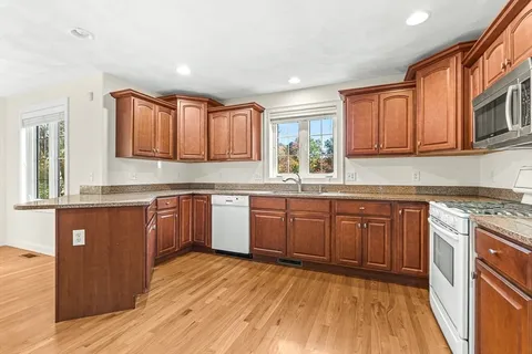 a kitchen with stainless steel appliances granite countertop wooden cabinets a sink and dishwasher a stove with wooden floor