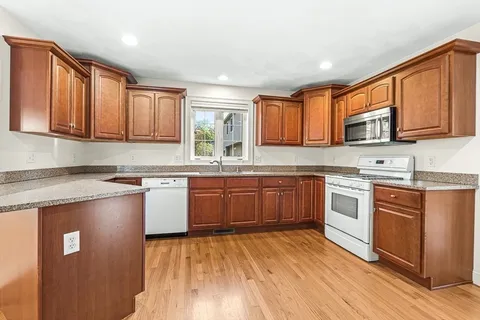 a kitchen with stainless steel appliances granite countertop a stove a sink dishwasher and a microwave oven with wooden cabinets