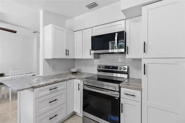 a kitchen with stainless steel appliances granite countertop white cabinets and a stove a oven with white countertops
