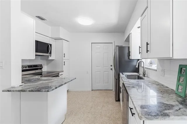 a kitchen with stainless steel appliances granite countertop a stove refrigerator and sink