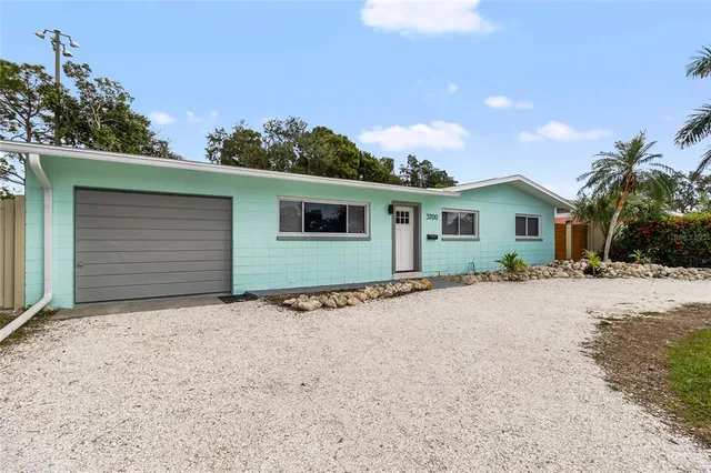 front view of house with potted plants and palm trees