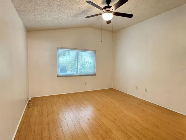 an empty room with wooden floor fan and windows