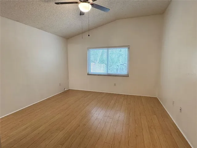 an empty room with wooden floor fan and windows