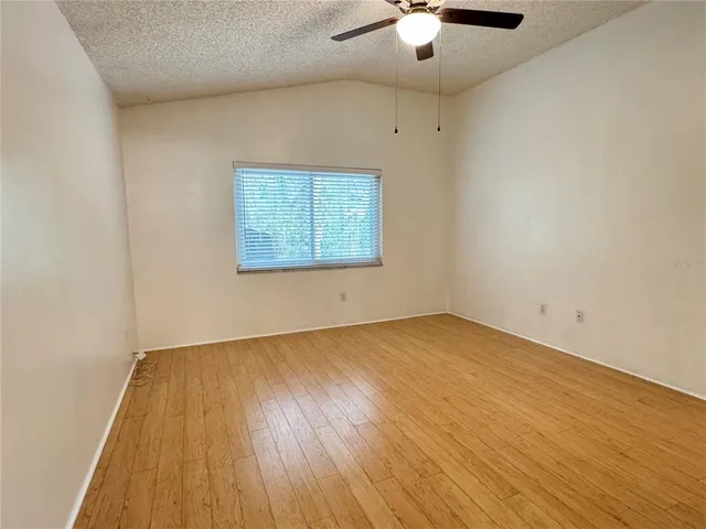 an empty room with a hardwood and ceiling fan