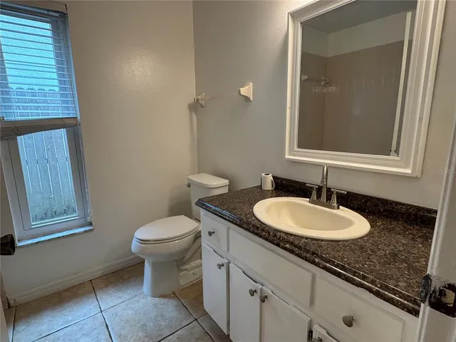a bathroom with a granite countertop toilet a sink and mirror