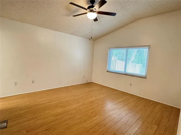 a view of an empty room with a window and wooden floor