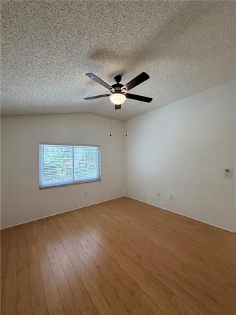 a view of empty room with wooden floor and fan