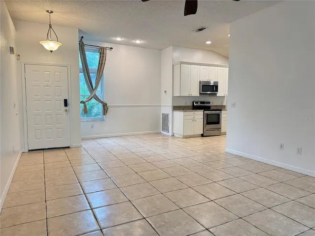 an empty room with kitchen and stainless steel appliances