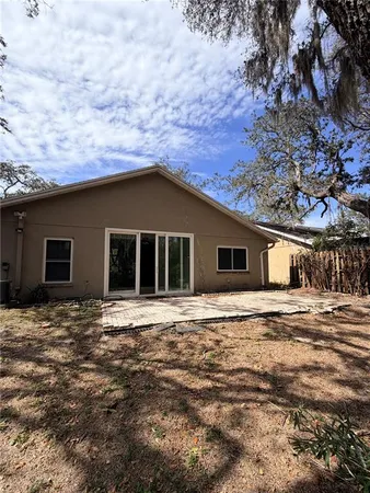 a big house with a big yard large trees and wooden fence
