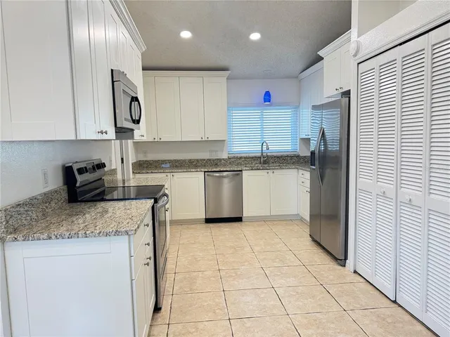 a kitchen with stainless steel appliances granite countertop a sink stove refrigerator and cabinets