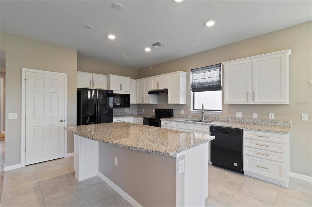 1530 Hyssop Loop North Port, FL 34289 - Photo 8 of 53 a kitchen with a refrigerator a sink a stove a microwave and cabinets