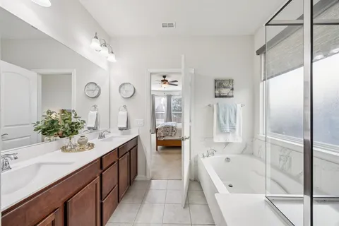 a bathroom with a granite countertop tub a double vanity sink and a large mirror