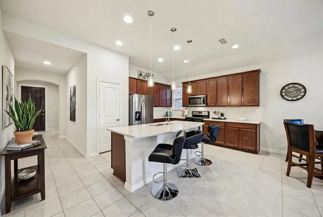 a kitchen with stainless steel appliances kitchen island granite countertop a refrigerator and a stove top oven with white cabinets