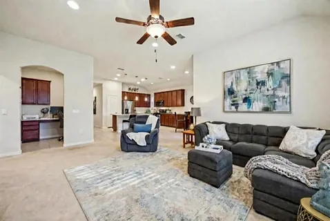 a living room with furniture kitchen view and a wooden floor