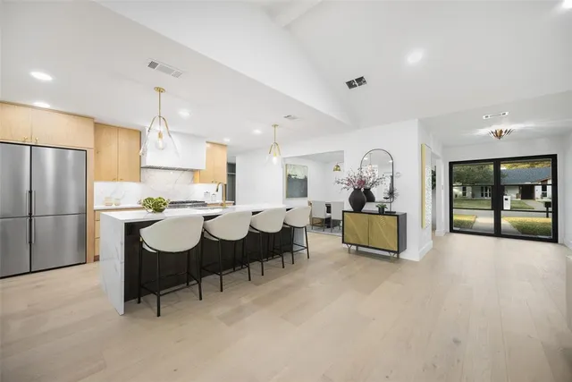 a very nice looking dining room with kitchen island furniture a sink a refrigerator and a counter top space