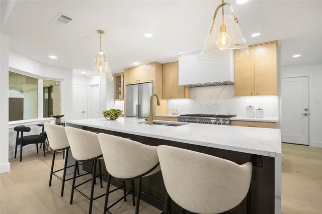 a kitchen with kitchen island granite countertop a table chairs sink and cabinets
