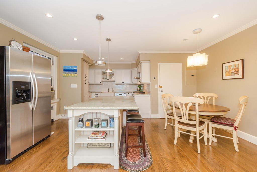 280 Beacon Street, Unit 65 Boston, MA 02116 - Photo 8 of 15 a kitchen with stainless steel appliances kitchen island granite countertop a refrigerator a stove a dining table and chairs with wooden floor