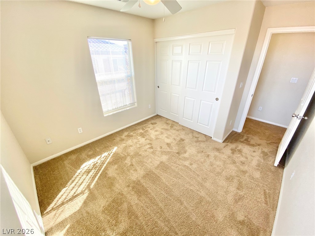 8569 Rhamus Court Las Vegas, NV 89149 - Photo 13 of 35 A well-lit bedroom features plush carpeting and a spacious closet, offering comfort and convenience.
