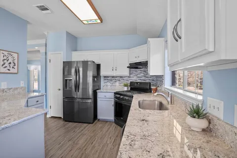 a kitchen with stainless steel appliances granite countertop a stove top oven a sink dishwasher a dining table and chairs