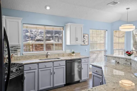 a kitchen with granite countertop a sink stainless steel appliances and window