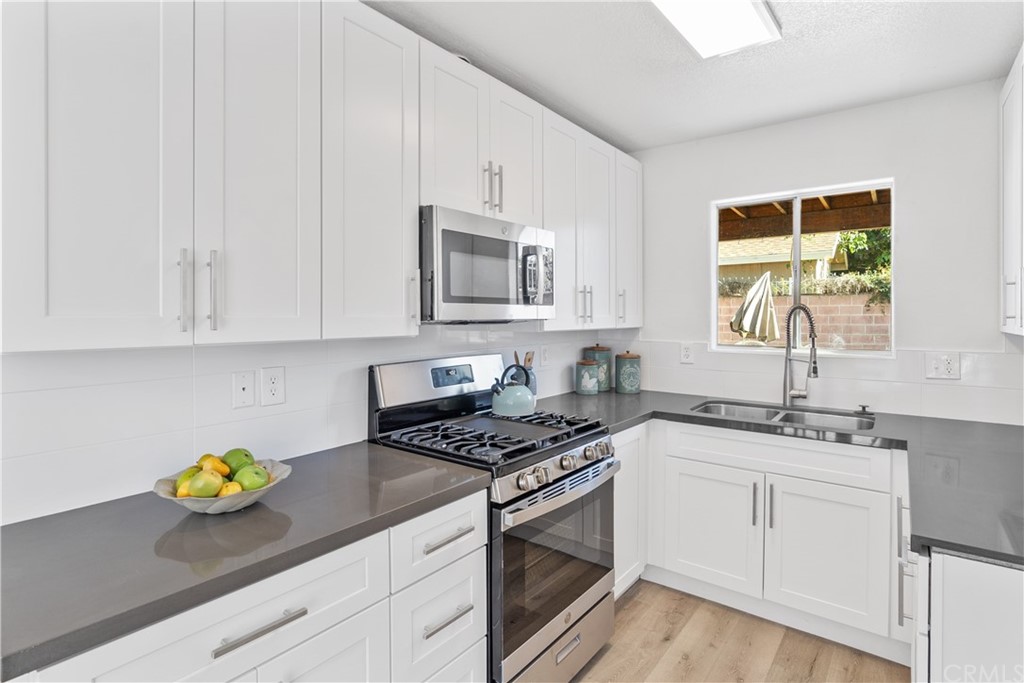 a kitchen with stainless steel appliances white cabinets and a stove a sink