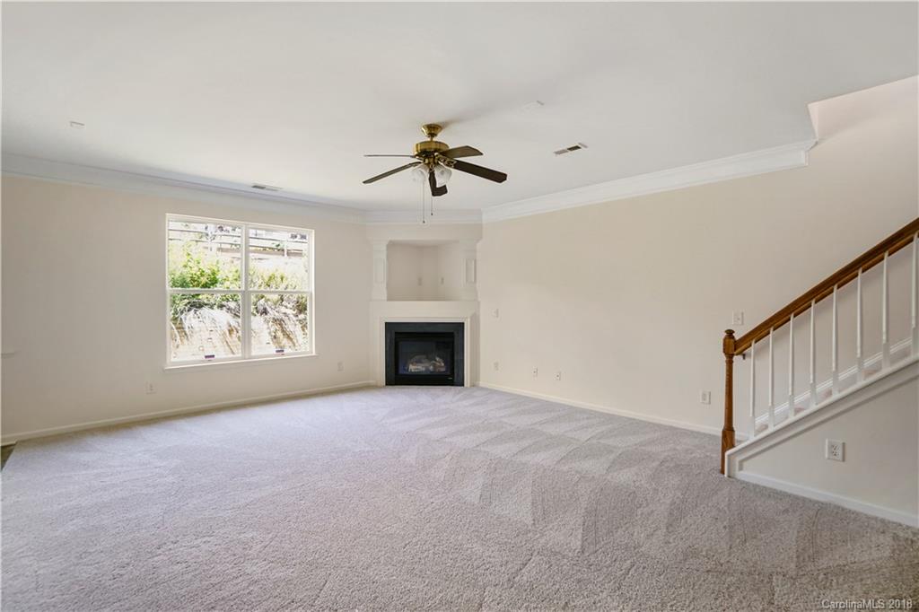 12918 Rothe House Road Charlotte, NC 28273 - Photo 11 of 25 an empty room with windows chandelier fan and fireplace