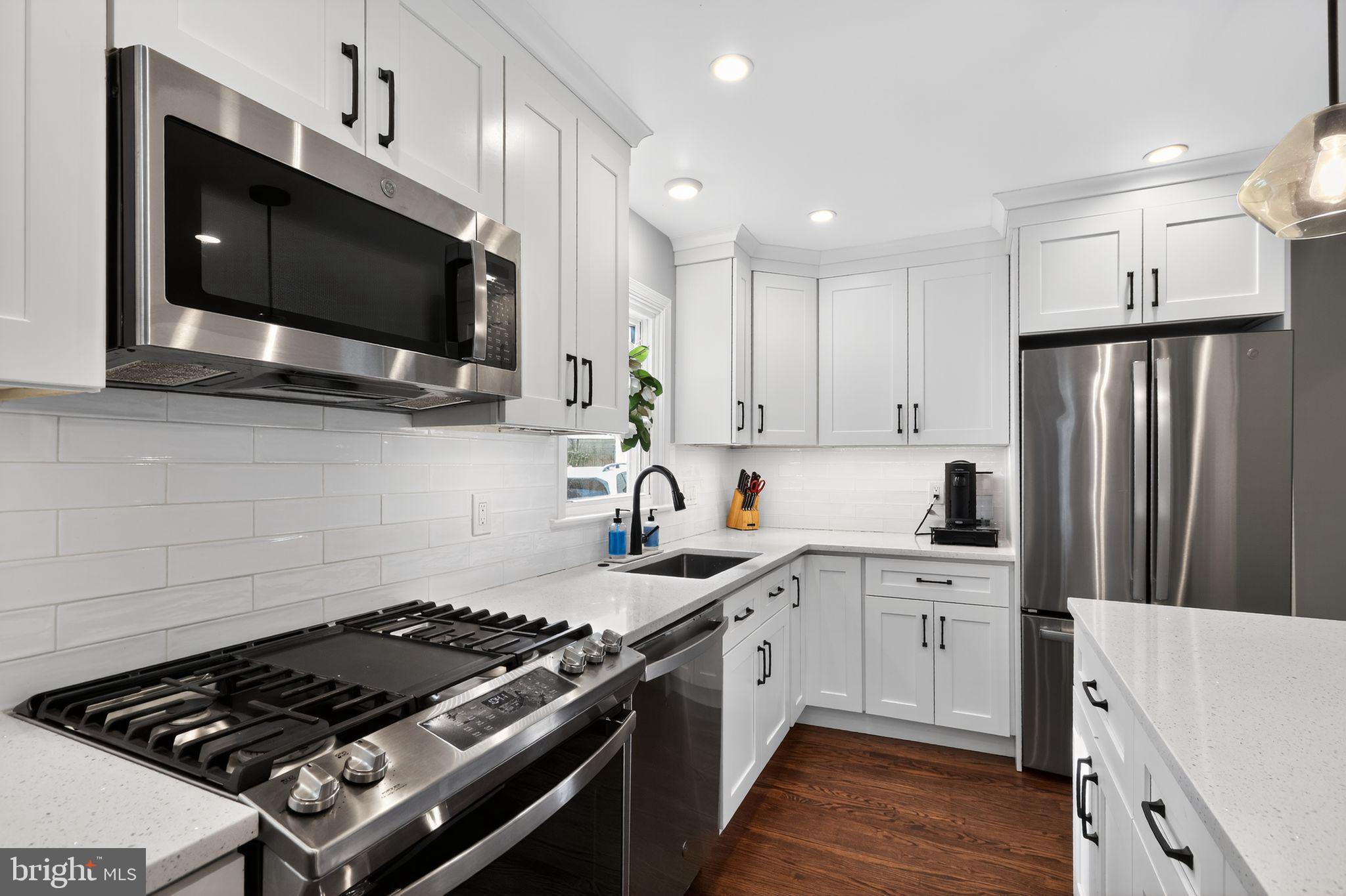 214 Lynbrooke Road Springfield, PA 19064 - Photo 12 of 42 a kitchen with stainless steel appliances a sink a stove a microwave cabinets and wooden floor