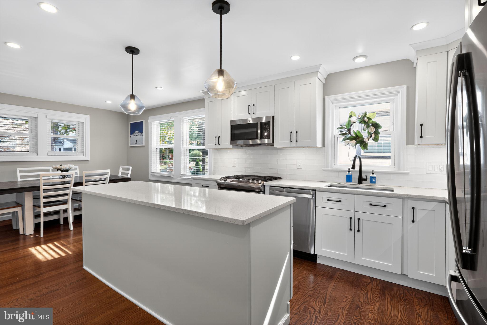 214 Lynbrooke Road Springfield, PA 19064 - Photo 13 of 42 a kitchen with stainless steel appliances granite countertop a sink stove a refrigerator and a dining table with wooden floor