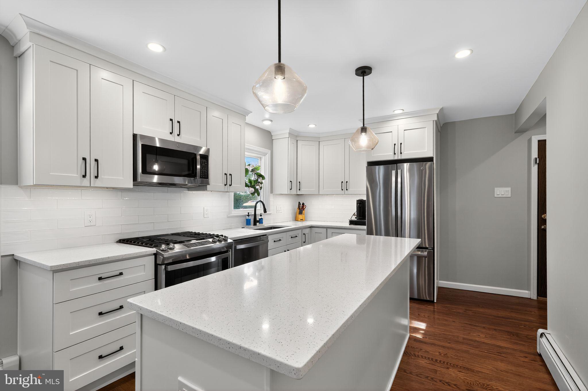 214 Lynbrooke Road Springfield, PA 19064 - Photo 14 of 42 a kitchen with stainless steel appliances granite countertop a sink a stove a refrigerator and island with wooden floor