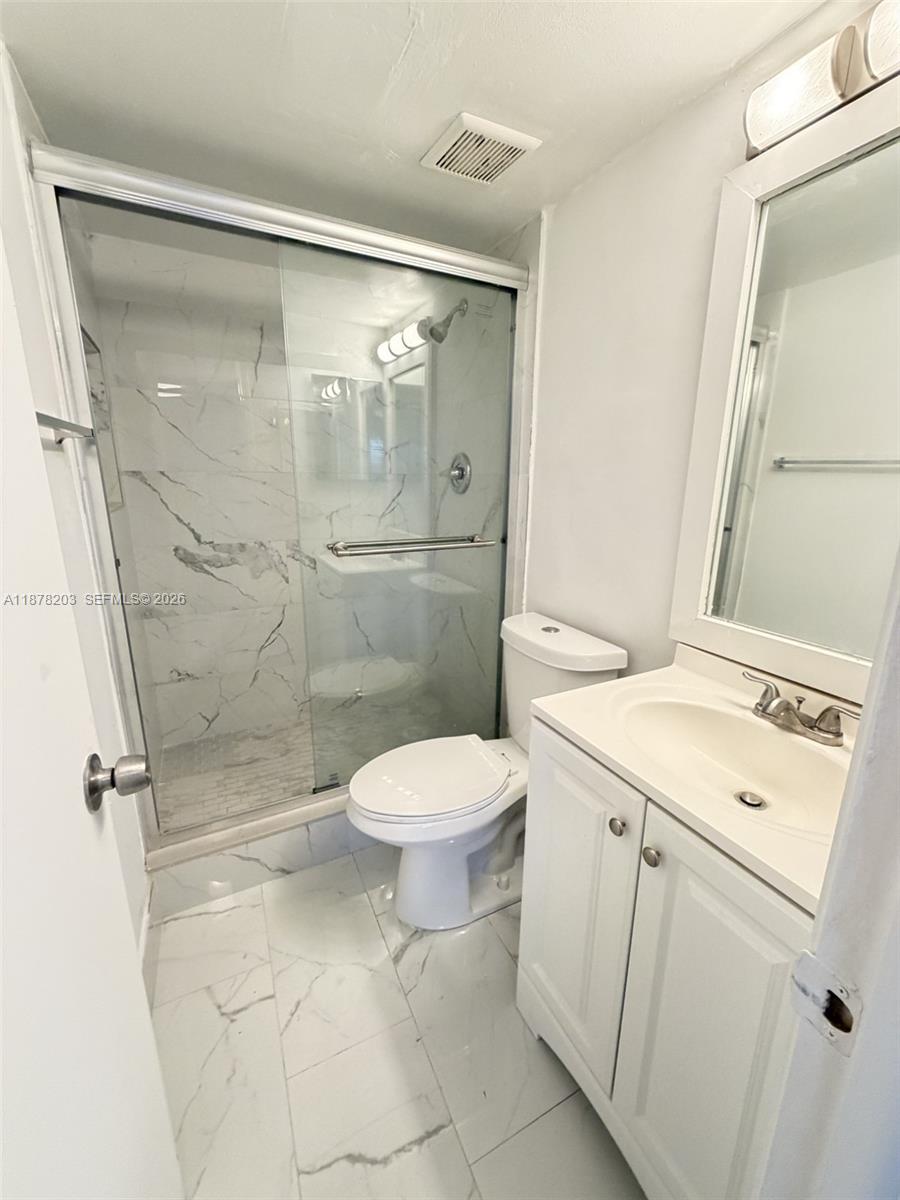 22605 Southwest 66th Avenue, Unit 403 Boca Raton, FL 33428 - Photo 13 of 20 a bathroom with a toilet sink and shower