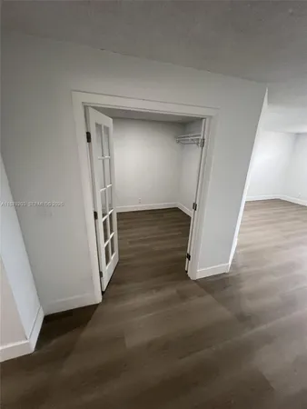 an empty room with wooden floor and a hallway