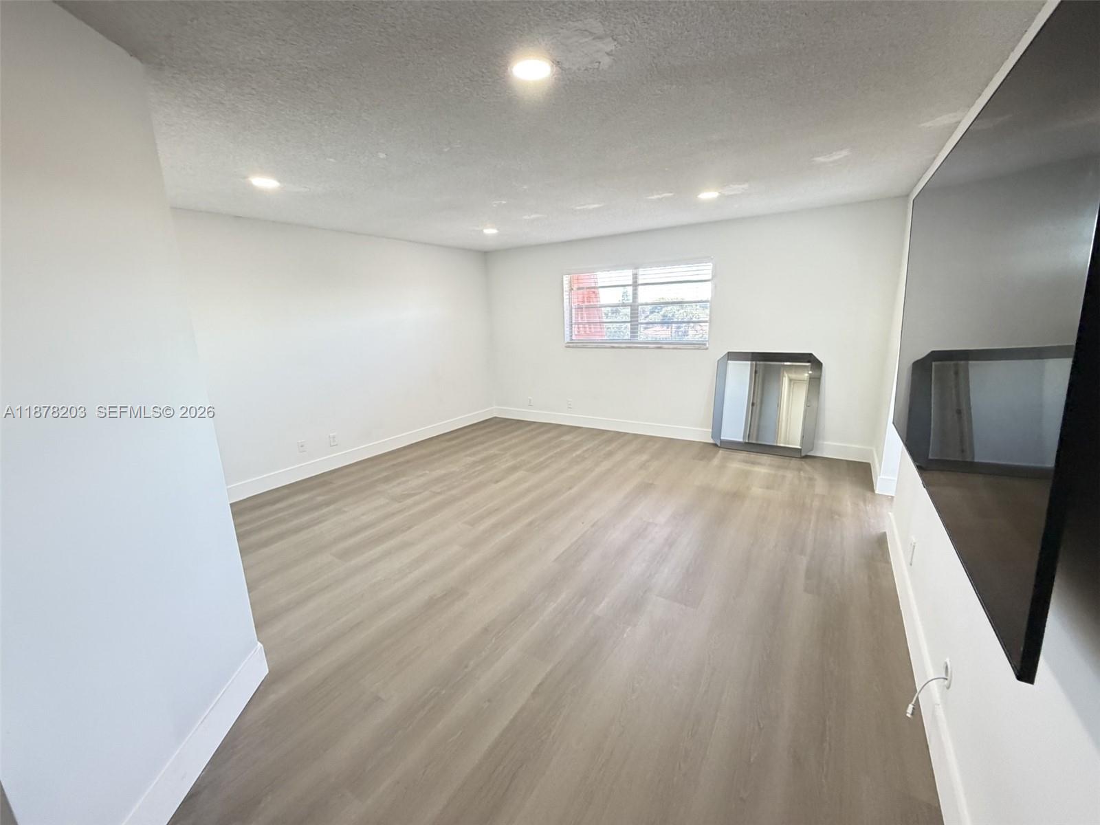 22605 Southwest 66th Avenue, Unit 403 Boca Raton, FL 33428 - Photo 6 of 20 an empty room with wooden floor and a window