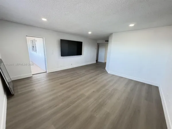 an empty room with wooden floor and a flat screen tv