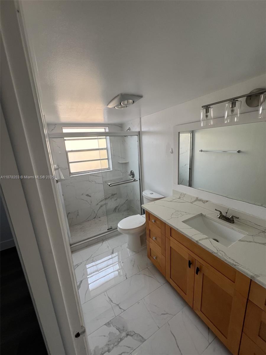 22605 Southwest 66th Avenue, Unit 403 Boca Raton, FL 33428 - Photo 9 of 10 a bathroom with a granite countertop sink a toilet and shower
