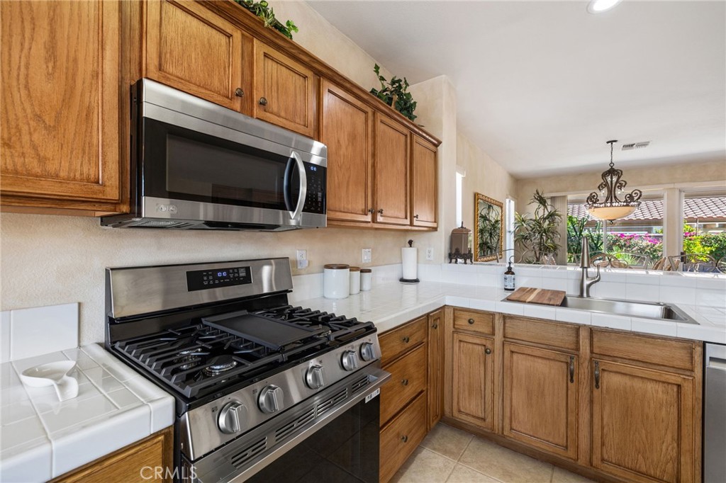 78770 Golden Reed Drive Palm Desert, CA 92211 - Photo 17 of 36 a kitchen with stainless steel appliances a sink dishwasher stove microwave and cabinets